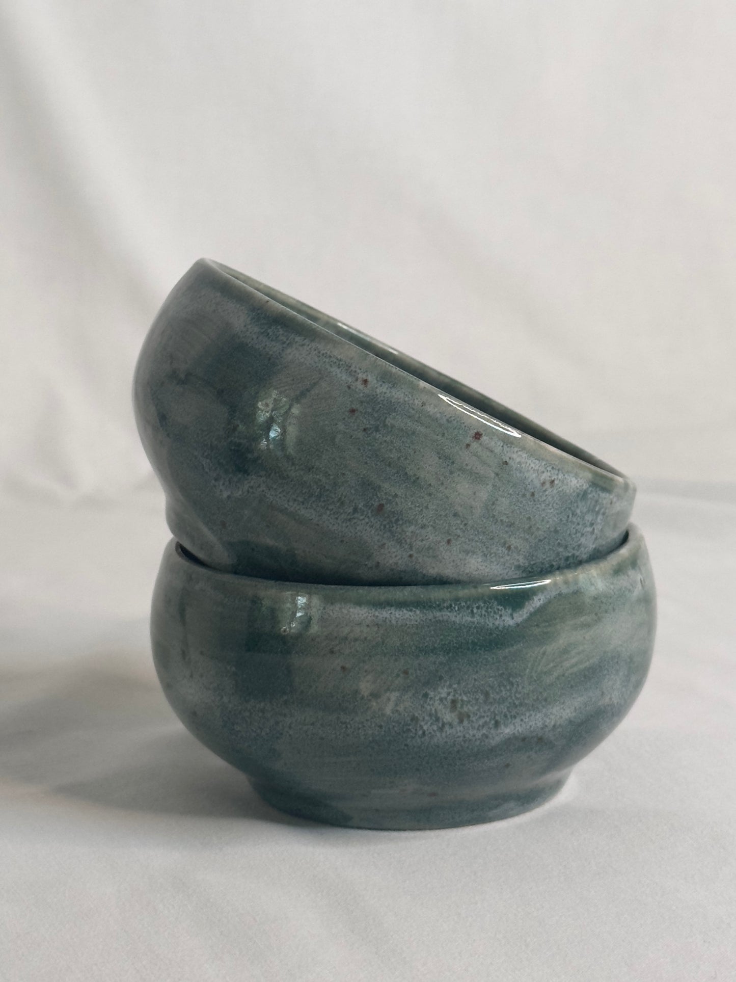Bol artisanal en céramique émaillée vert foncé, avec des nuances de gris et des détails mouchetés. Idéal pour les petits déjeunés, soupes, salades ou autres plats, il ajoute une touche élégante et naturelle à la table.