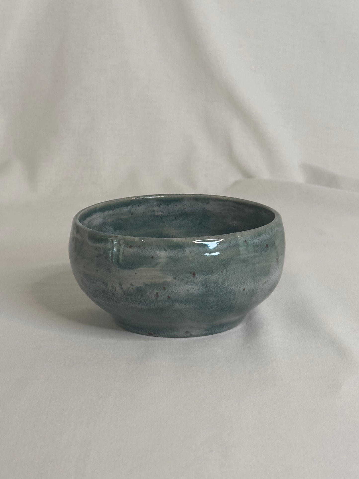 Bol artisanal en céramique émaillée vert foncé, avec des nuances de gris et des détails mouchetés. Idéal pour les petits déjeunés, soupes, salades ou autres plats, il ajoute une touche élégante et naturelle à la table.