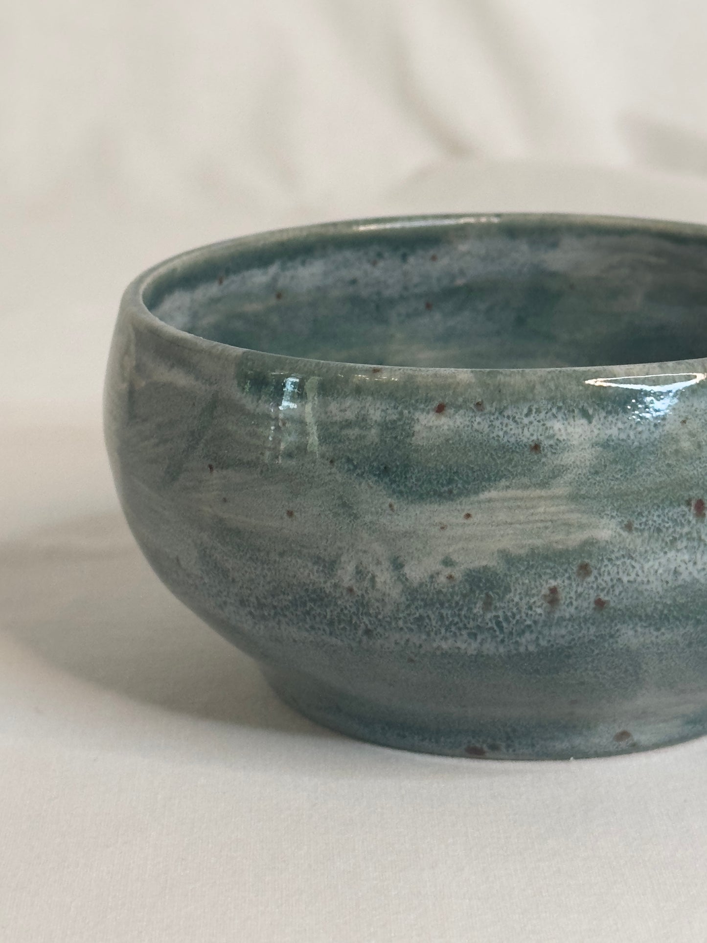 Bol artisanal en céramique émaillée vert foncé, avec des nuances de gris et des détails mouchetés. Idéal pour les petits déjeunés, soupes, salades ou autres plats, il ajoute une touche élégante et naturelle à la table.