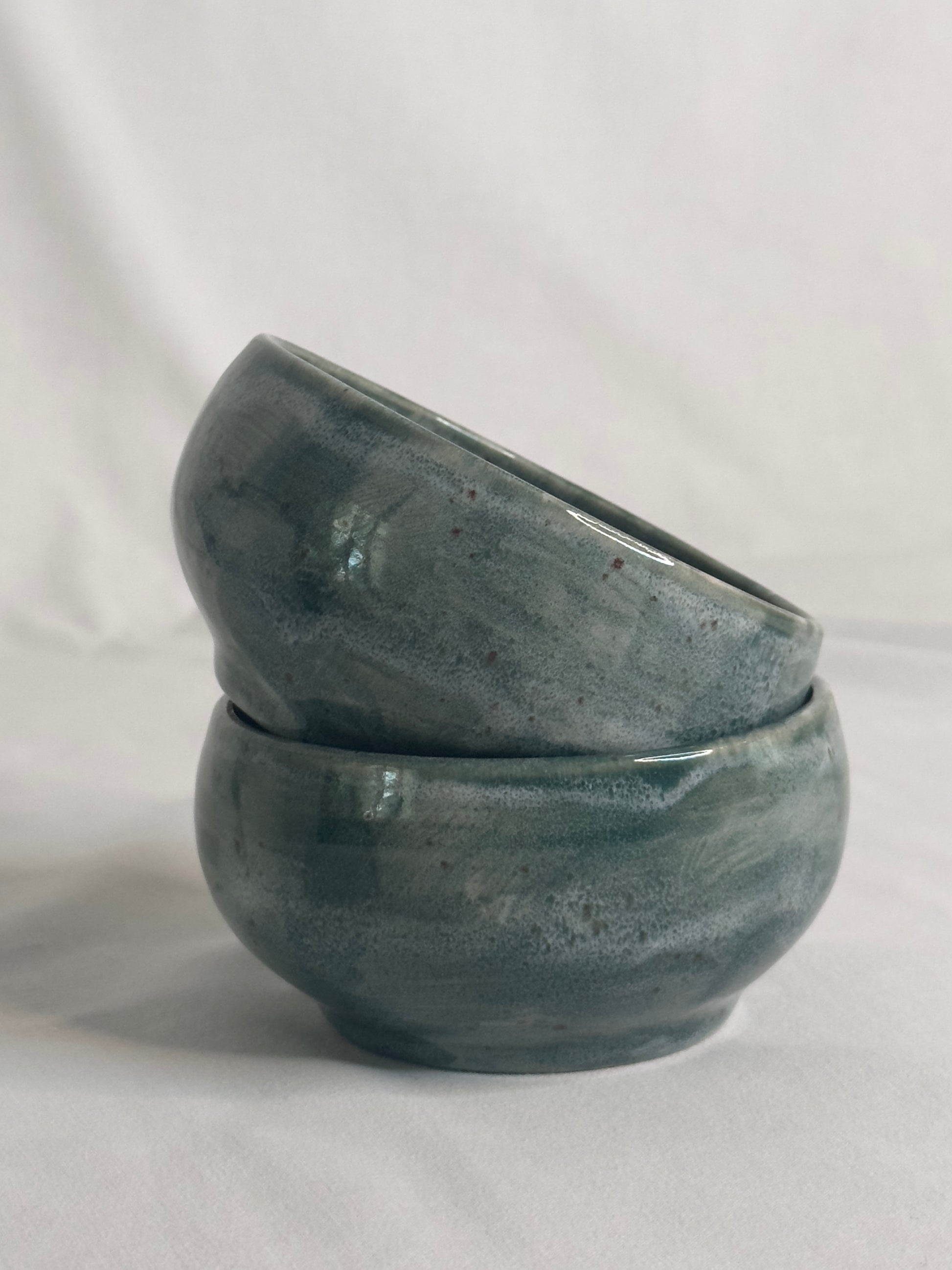 Bol artisanal en céramique émaillée vert foncé, avec des nuances de gris et des détails mouchetés. Idéal pour les petits déjeunés, soupes, salades ou autres plats, il ajoute une touche élégante et naturelle à la table.
